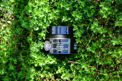 Organic Achoo Herbal Salve for natural decongestant relief, surrounded by fresh green thyme, showcasing raw beauty and farm-to-bottle authenticity.