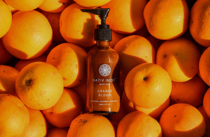 Organic Orange Bloom Body Milk among fresh oranges, highlighting natural and raw beauty with authentic ingredients from Himalayas.